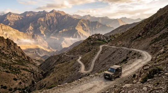 Remote mountain village accessed through winding dirt road with a 4x4 vehicle navigating challenging terrain