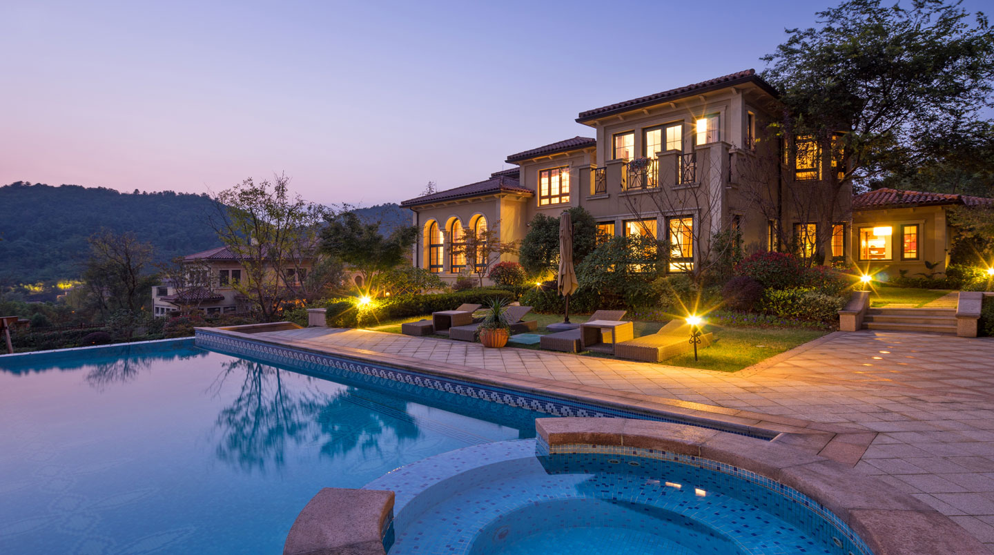 Close-up of hands holding a smartphone displaying a blurred calendar app, kitchen counter visible in the background suggesting self-catering context, natural indoor lighting