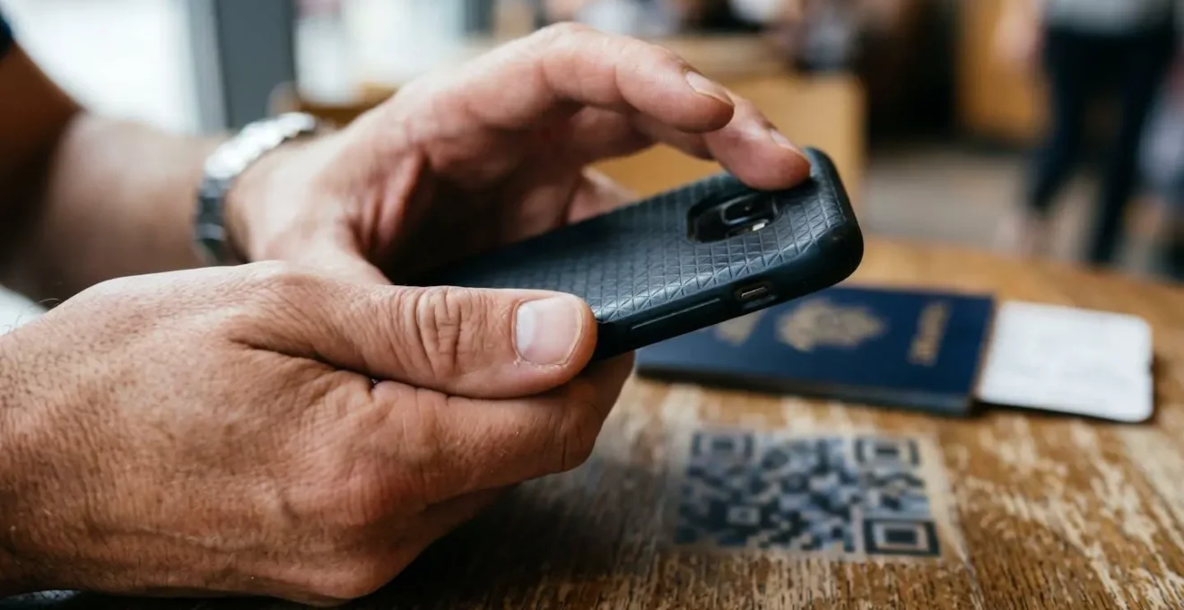 Hands holding a smartphone, with fingers positioned to scan a QR code for eSIM activation, representing pre-travel setup.